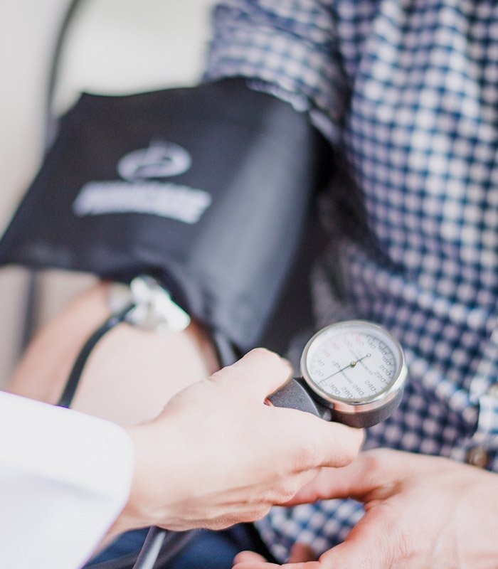 Close Up of Doctor Measuring Blood Pressure of Patient Wearing Checkered Shirt