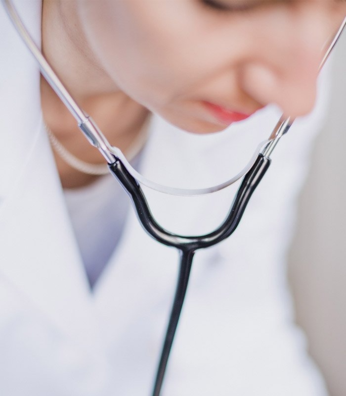 Focused Female Doctor Wearing White Coat and Stethoscope During Patient Examination